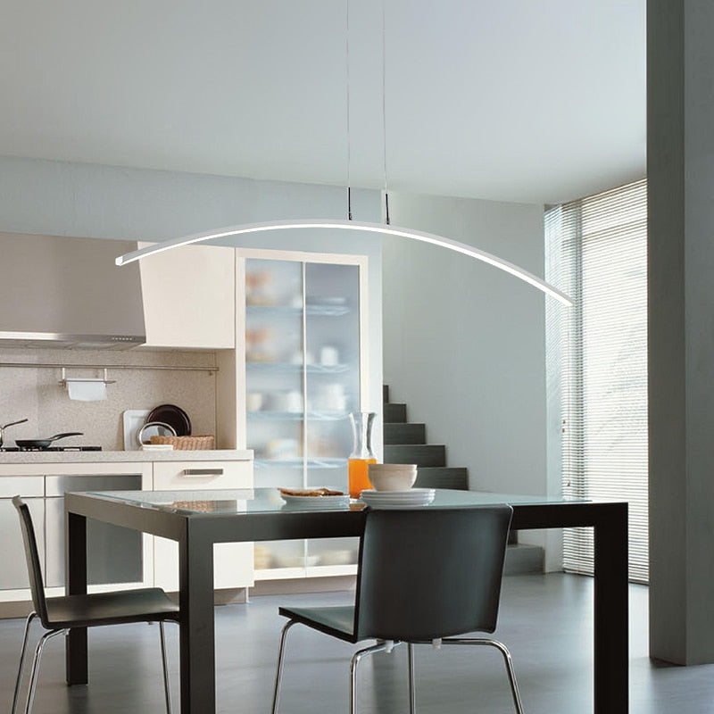 Sleek and Modern LED pendant light with a curved design, installed over a dining table in a bright interior setting.